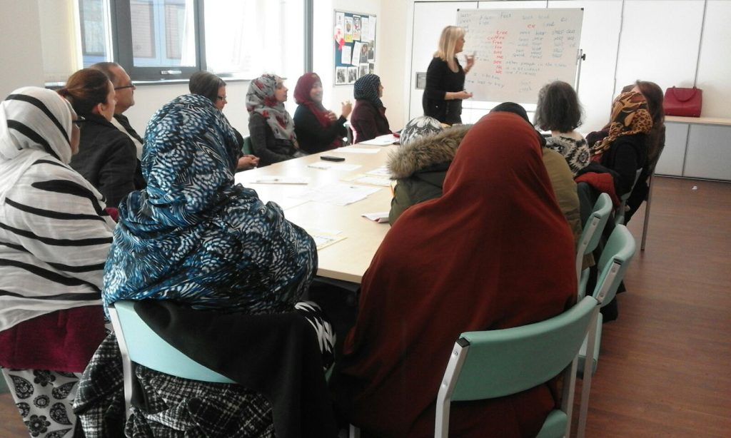 Adults sitting around a table with a teacher standing at the front