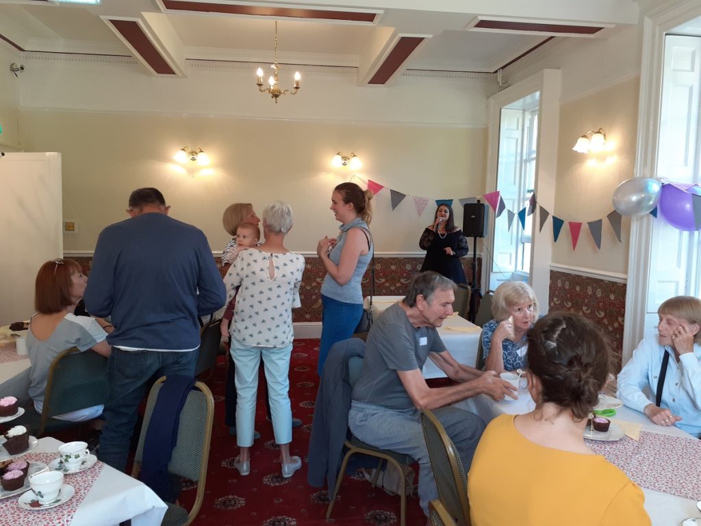 People chatting, with singer in background, at Dementia Cafe launch