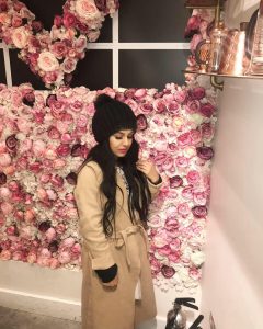 photo of Sayrish standing in front of a wall of pink flowers