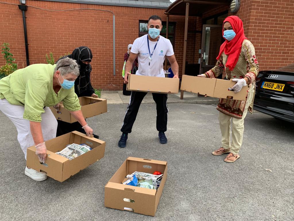 photo of people wearing masks, carrying boxes of food