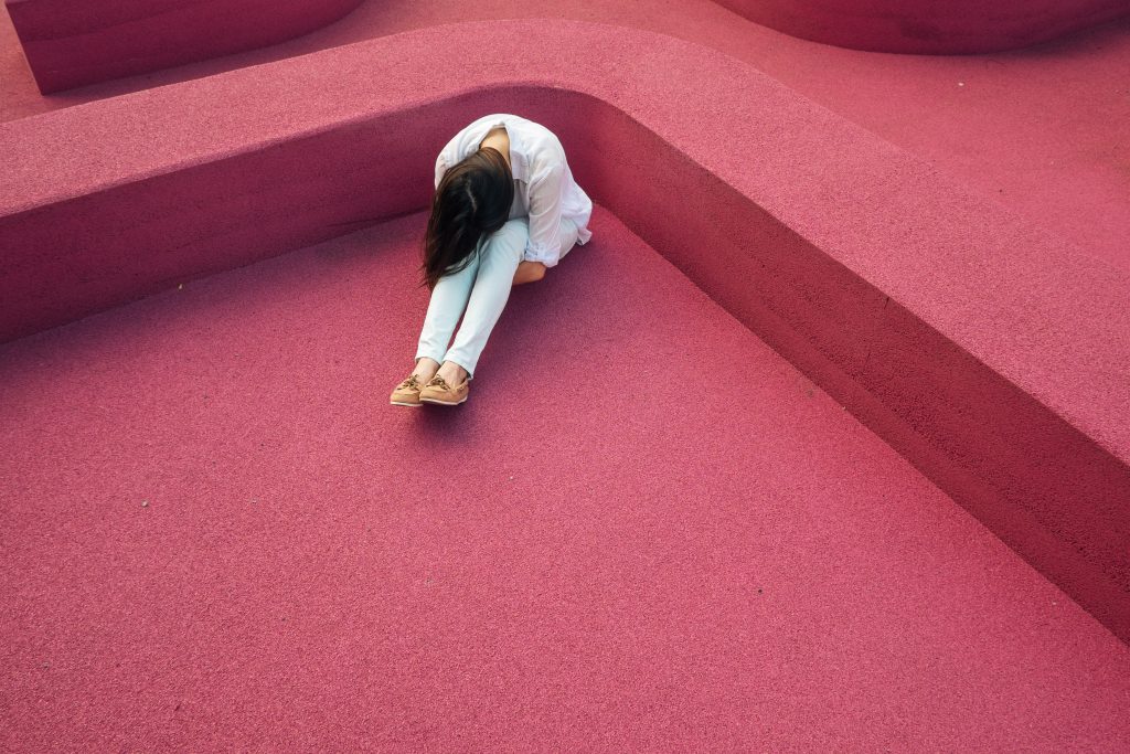 photo of woman sitting on floor with head bowed