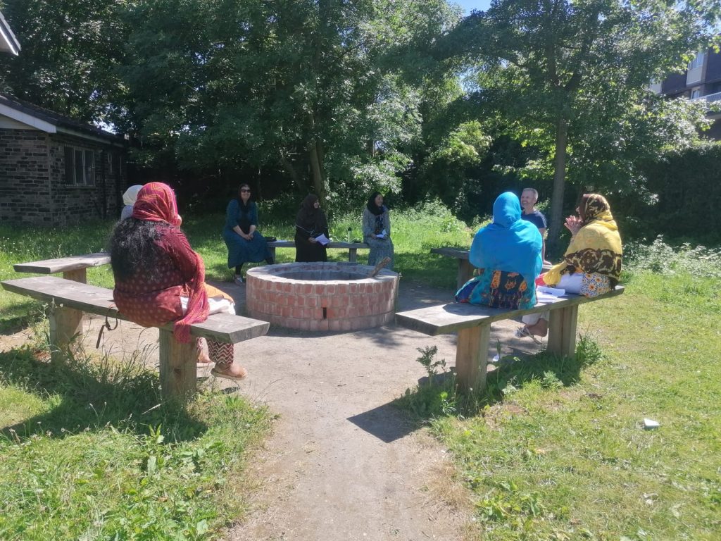 photo of women sitting in a circle on benches chatting