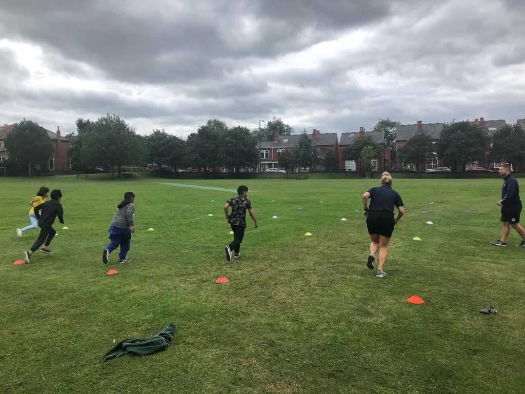 photo of children and adult running across a park