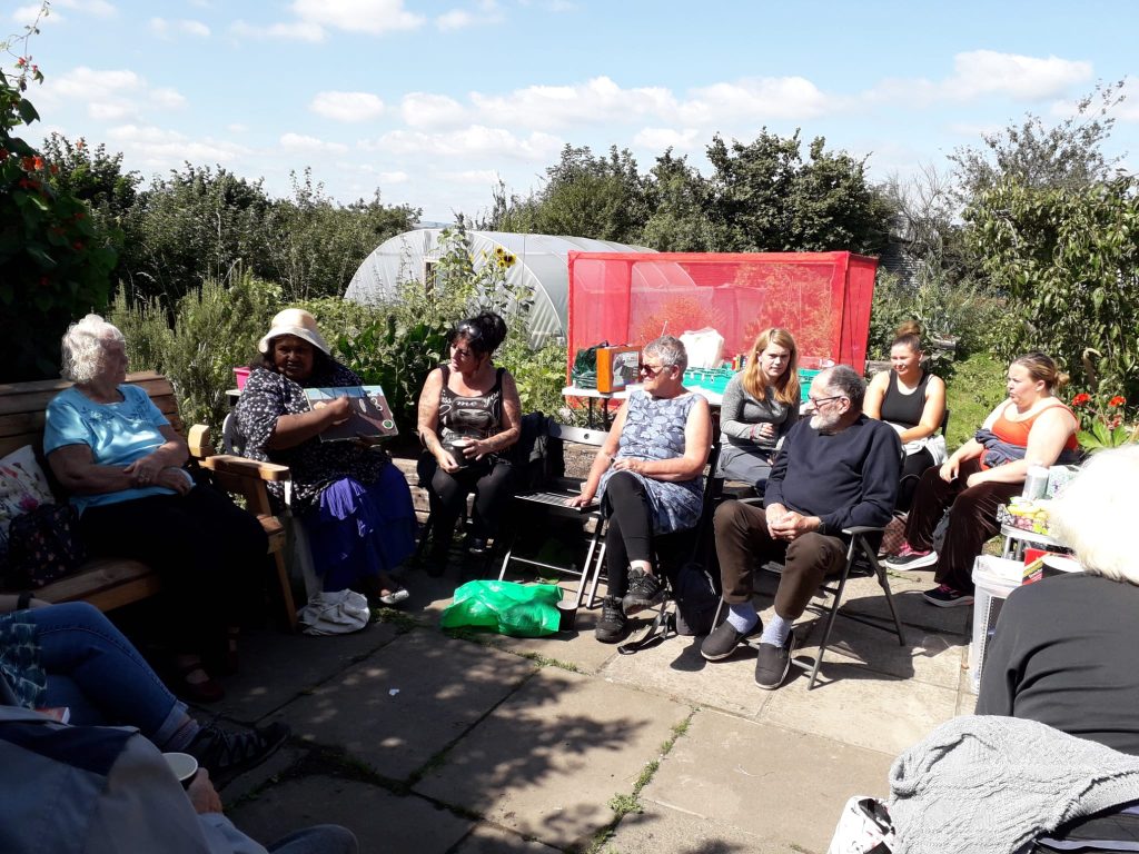 photo of group of people in sunshine at allotment with artwork
