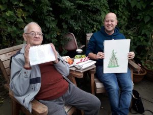 photo of 2 men holding a artwork they have done