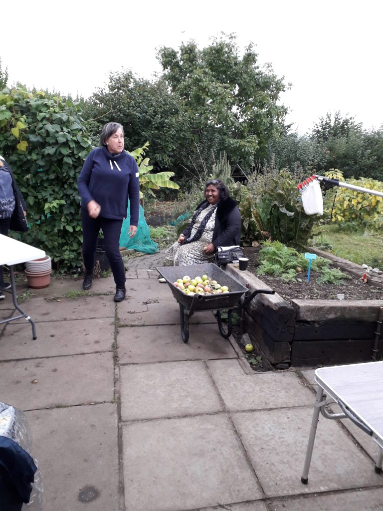 2 women on an allotment - 1 seated, 1 standing