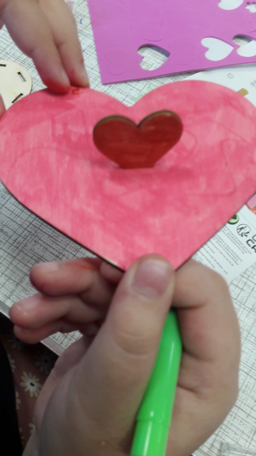 a pink wooden heart being held in a child's hands