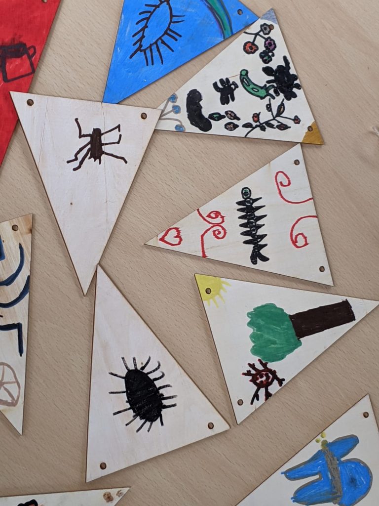 wooden bunting on a table coloured by pictures done by children