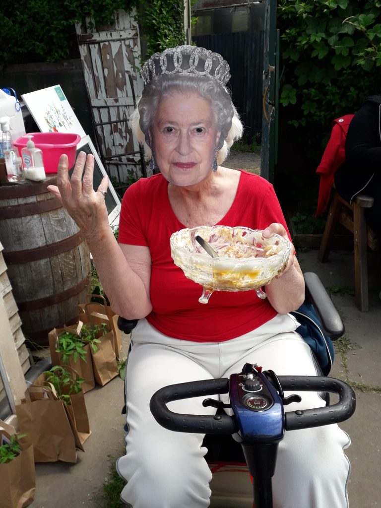 woman sitting on mobility scooter wearing mask of Queen Elizabeth 2
