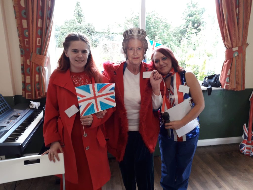 3 women standing together in red, white and blue, with Jubilee decorations
