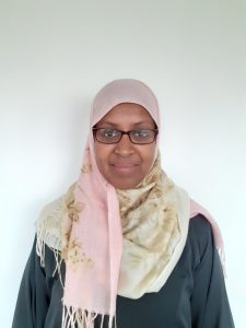 photo of woman wearing headscarf and glasses, smiling to camera