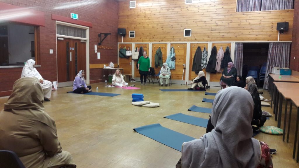 women in a community hall doing yoga together