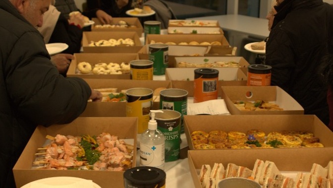 buffet food on a table with people helping themselves
