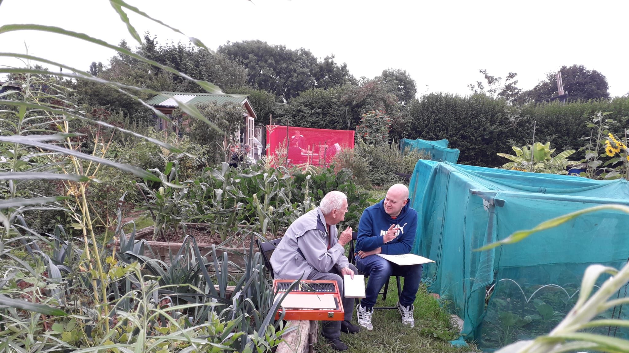 photo of 2 men talking and doing artwork at allotment