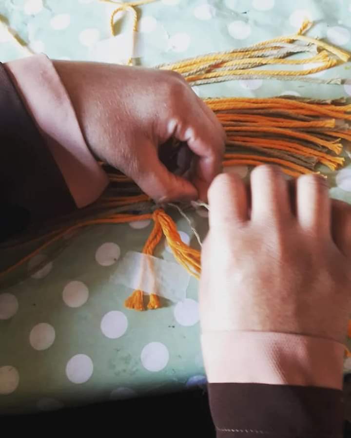 a pair of hands working with some orange and brown wool