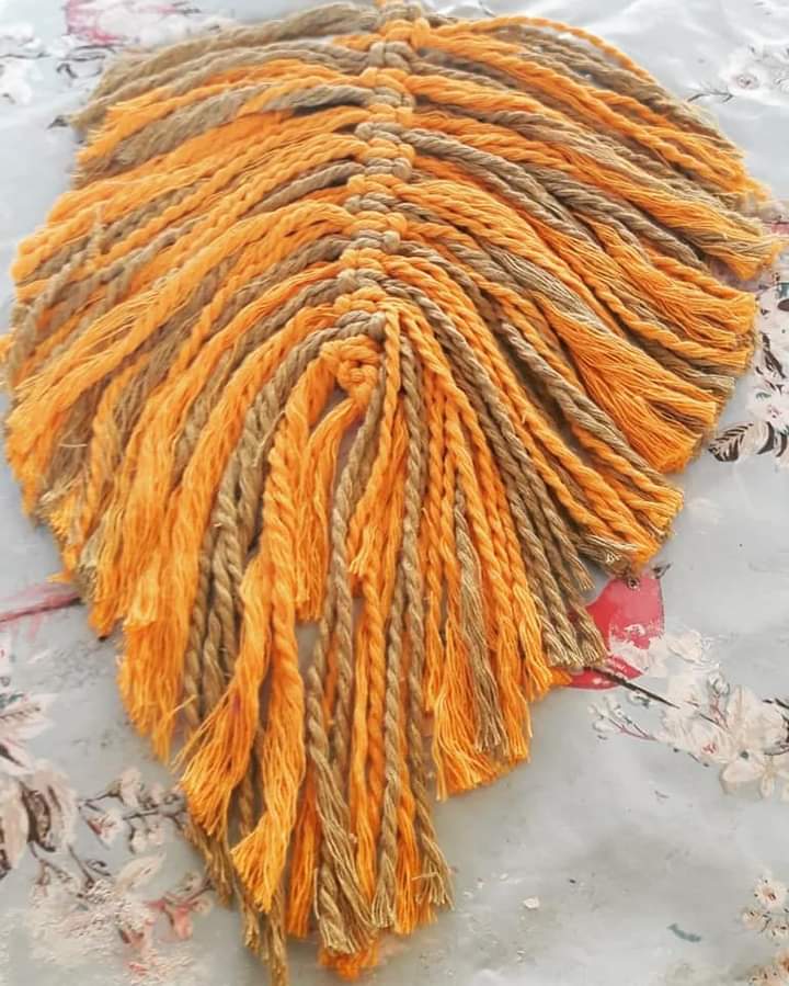 a brown and orange striped feather shape made using macrame