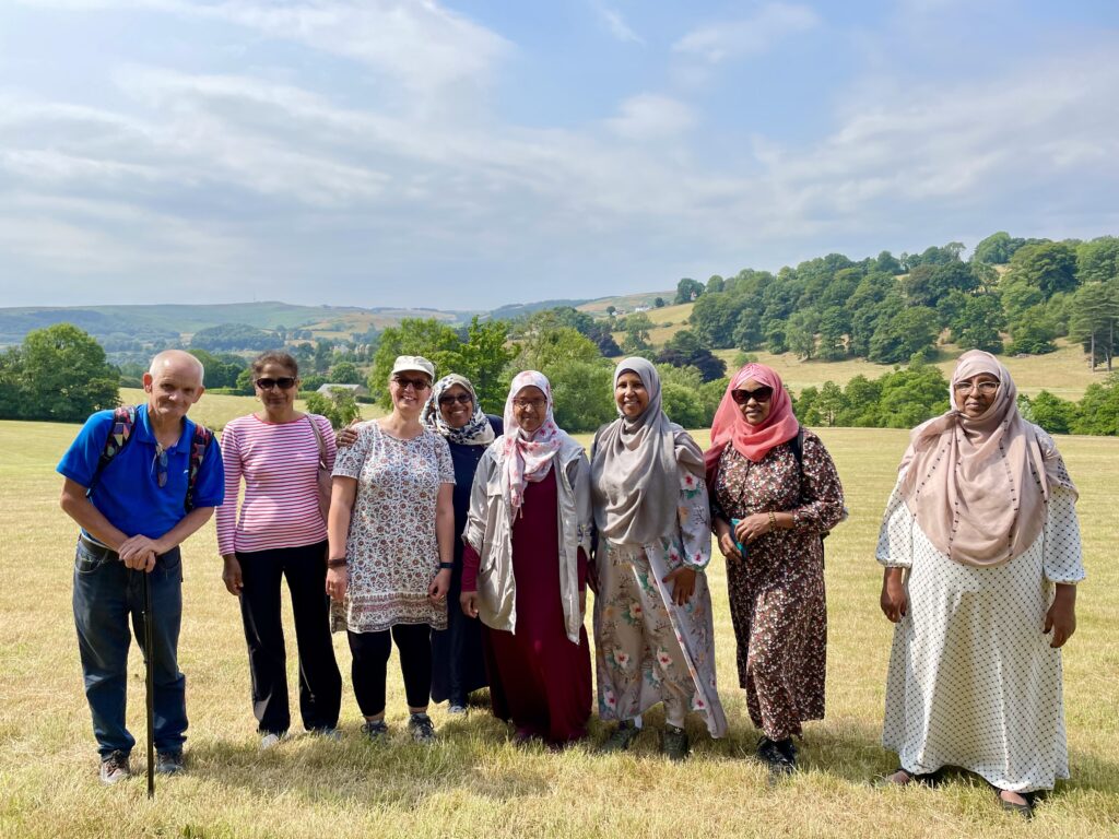 group of people standing in a field in the countryside, smiling to camera