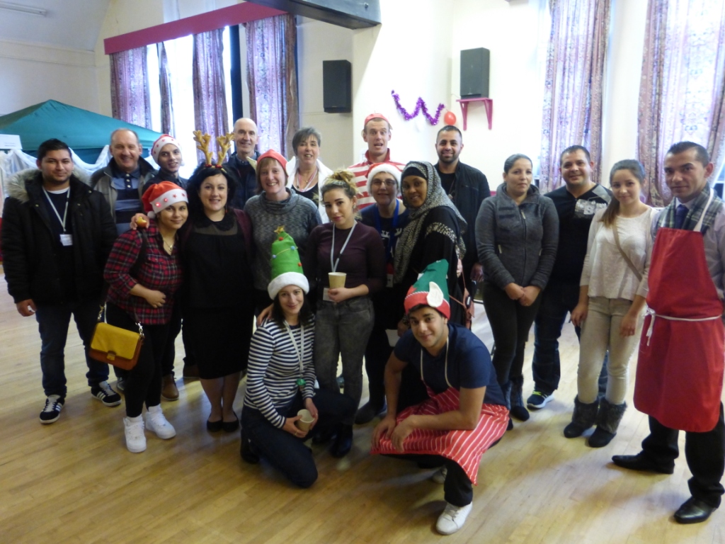 group of adults smiling to camera, some wearing Christmas hats