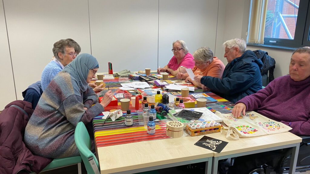 Group of people seated around a table doing crafts together