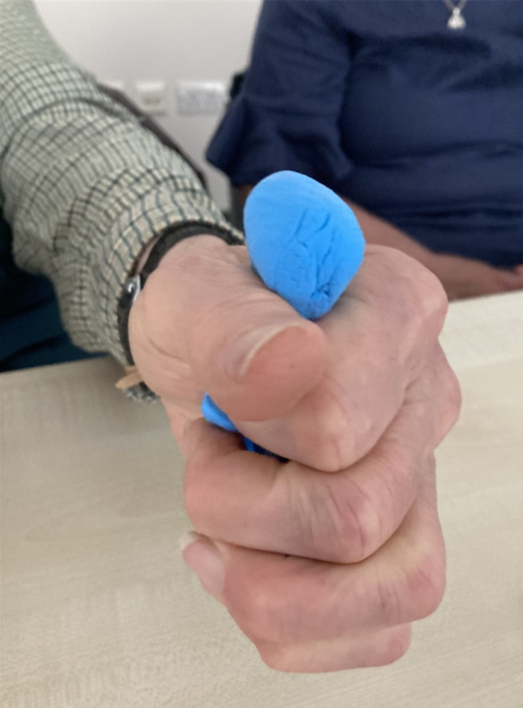 blue clay being squashed in a man's hand