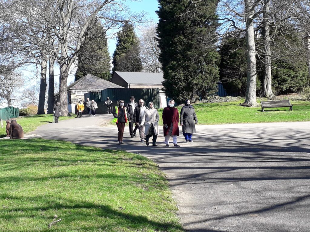 group of people walking towards the camera on a footpath in a park