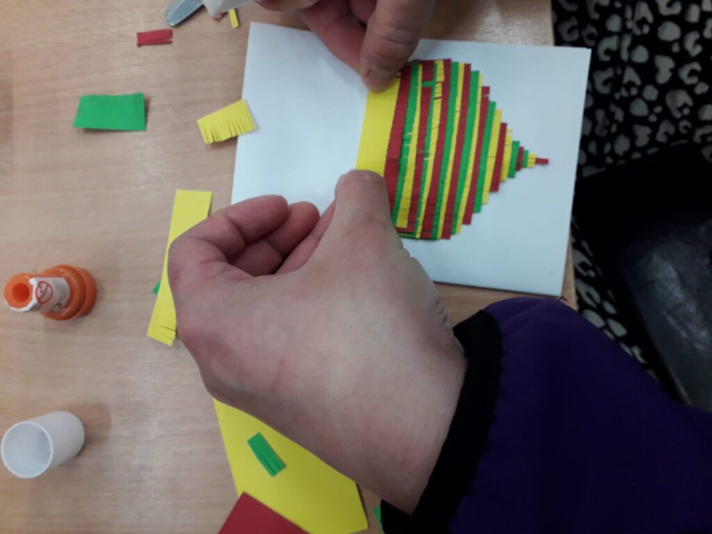hands folding colourful strips of paper into a shape