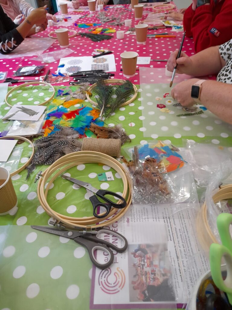 people's hands making craft items at a table covered with craft materials
