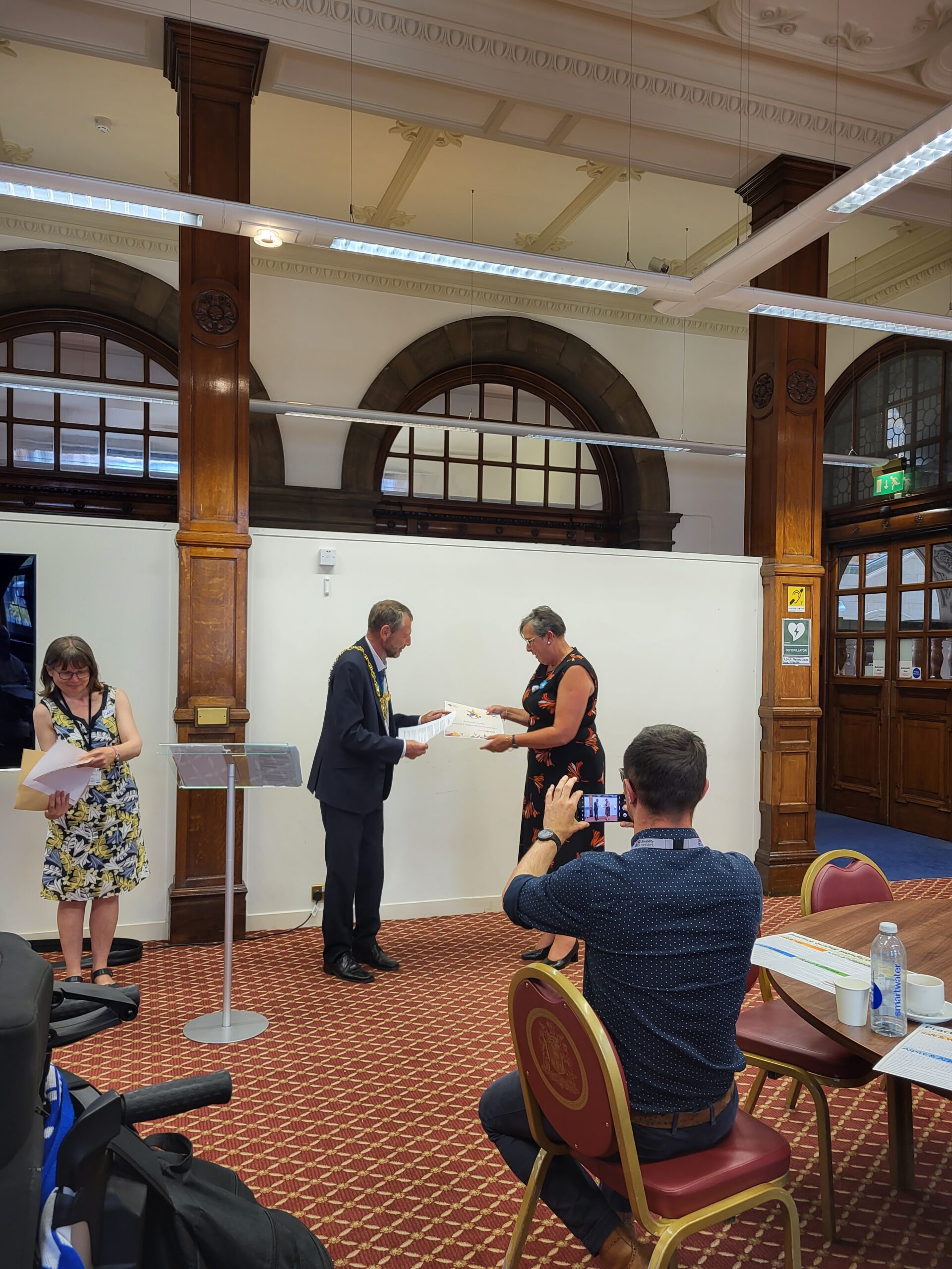 woman standing and receiving an award certificate from the Lord Mayor of Sheffield