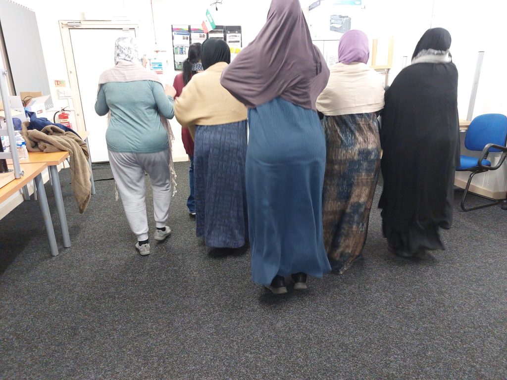Women photographed from behind standing in a classroom.
