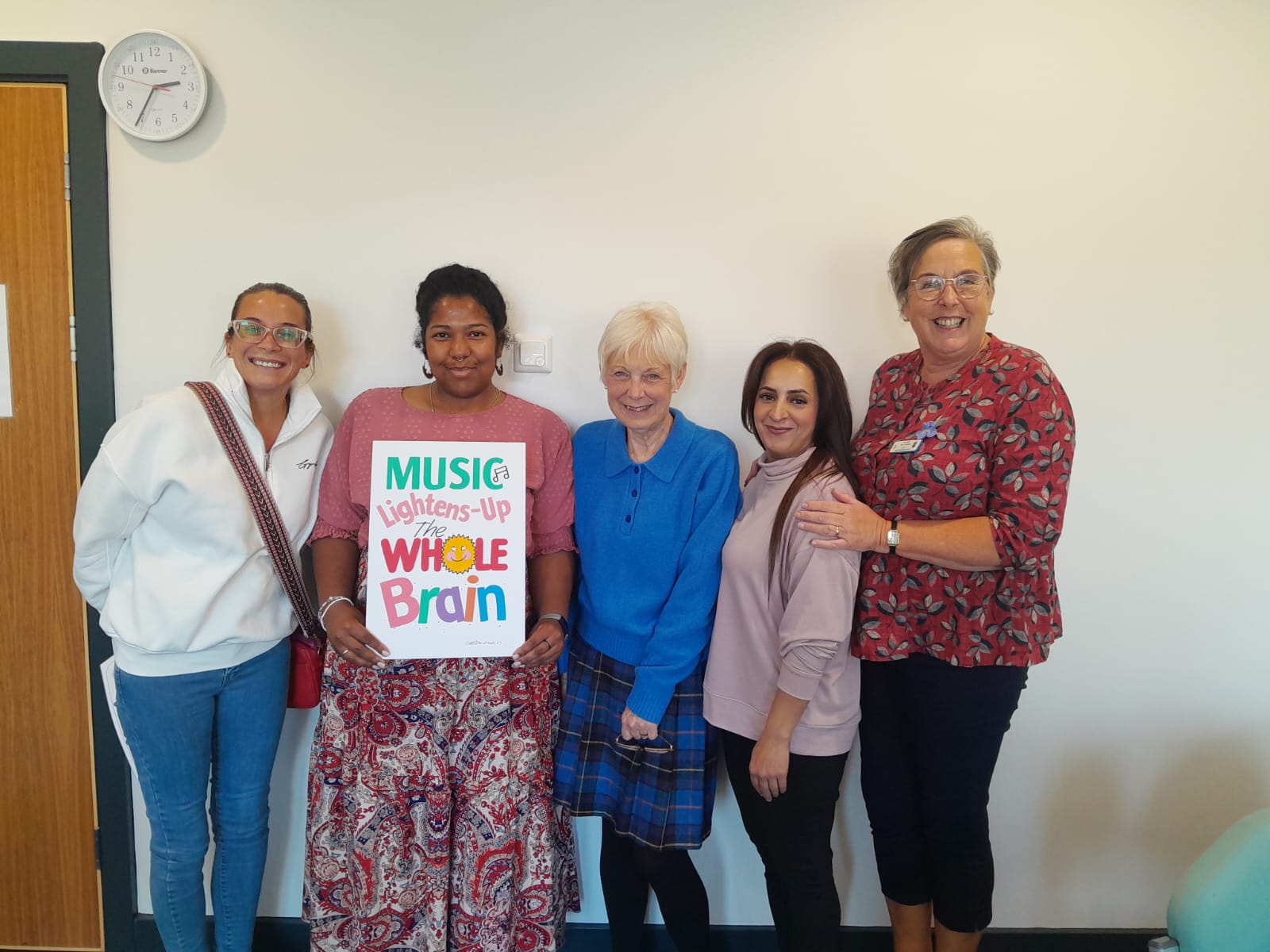 5 people smiling to camera with a sign saying Music Lightens Up the Whole Brain